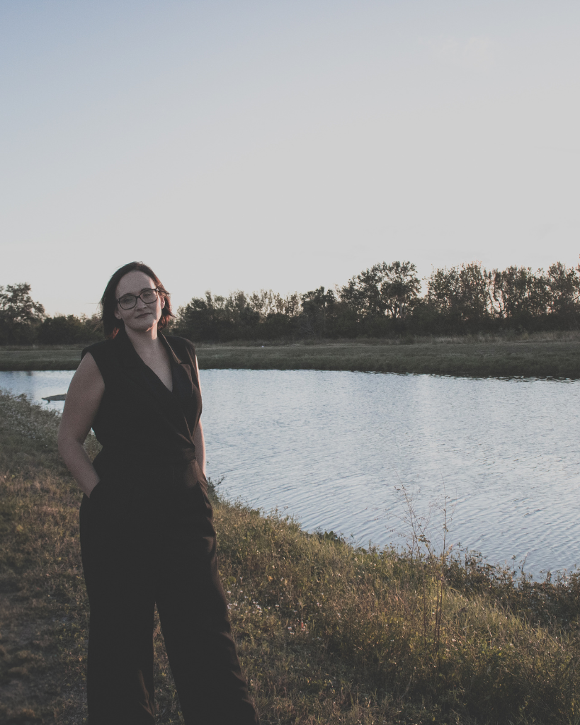 Professional businesswoman standing near a calm lake during sunset, representing focus, productivity, and balance—featured image for Lazer Focused productivity tools blog post.