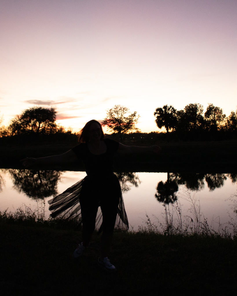 Silhouette of a woman dancing by a peaceful lake at sunset, symbolizing freedom, balance, and reclaiming time with smarter systems.